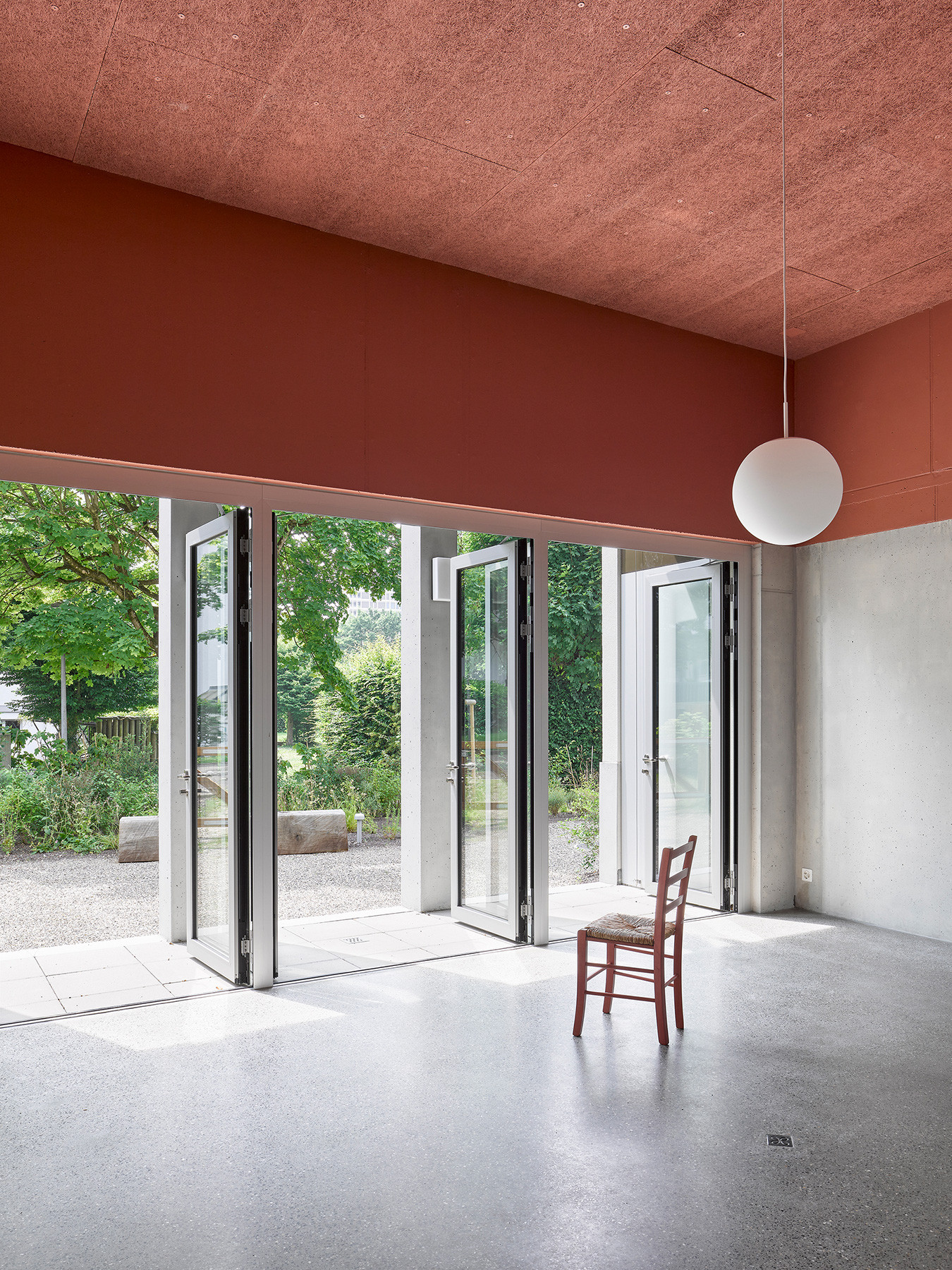 Innenaufnahme des überhohen Gemeinschaftsraums «Gartenhalle» mit Blick in den Garten.
