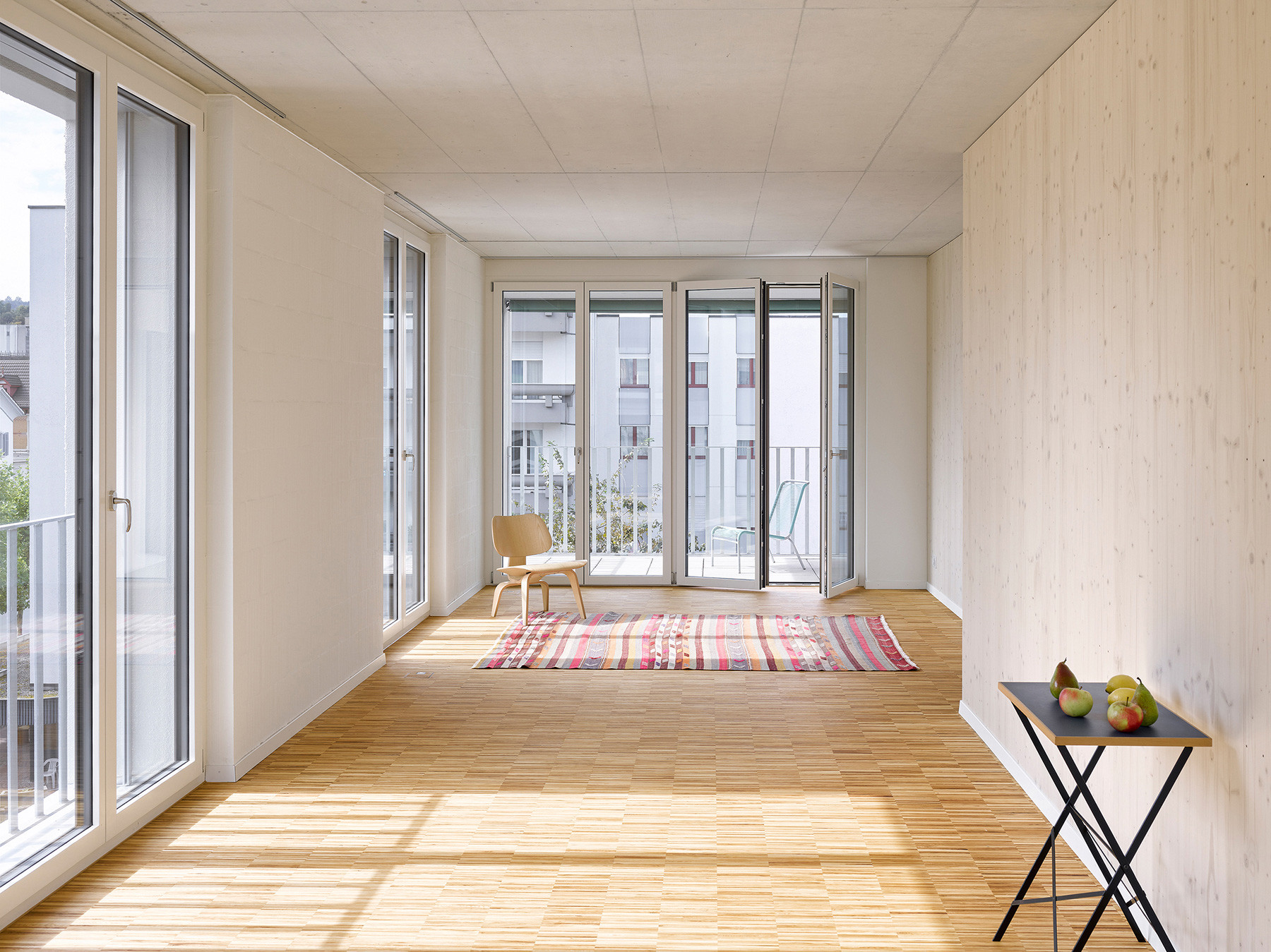 Wohnraum mit grossen Fenstern und Zugang zum Balkon.