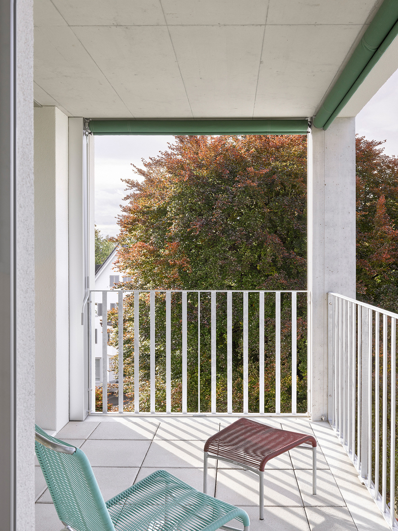 Balkon mit Holzgeländer und Blick ins begrünte Wohnumfeld.